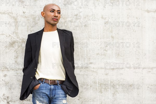 Pensive gay Black man leaning on concrete wall