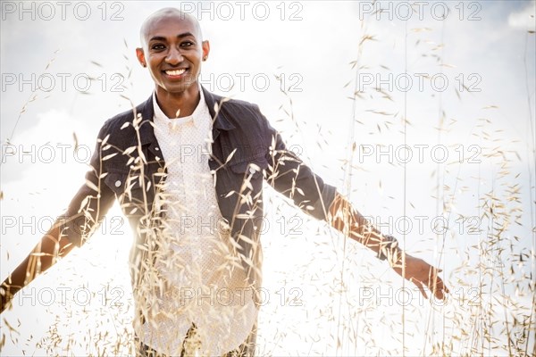 Smiling gay Black man standing in tall grass