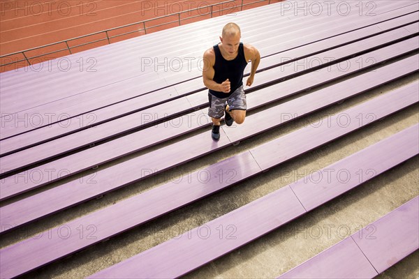 Caucasian man running on purple bleachers