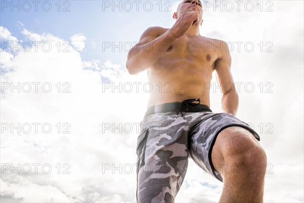 Caucasian man with bare chest running under cloudy sky