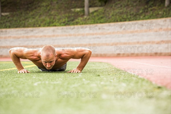 Caucasian man doing push-ups on sports field