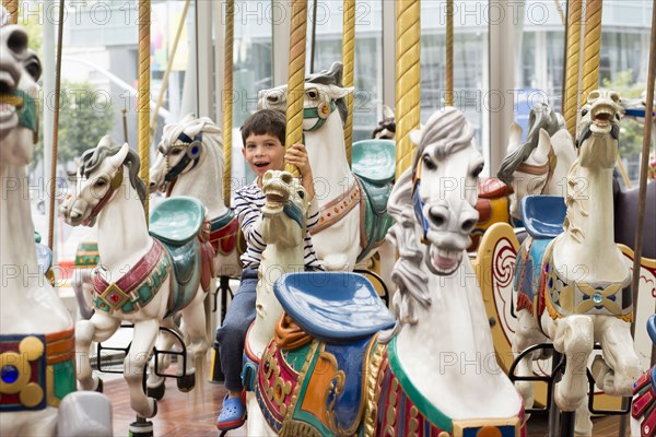 Mixed race boy riding carousel