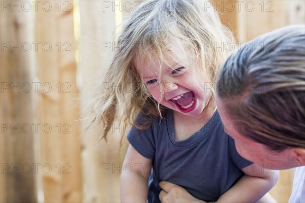 Caucasian mother holding laughing baby daughter