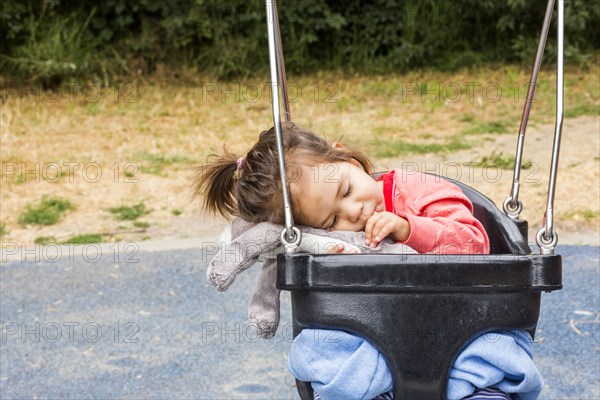 Caucasian baby girl sucking thumb in swing