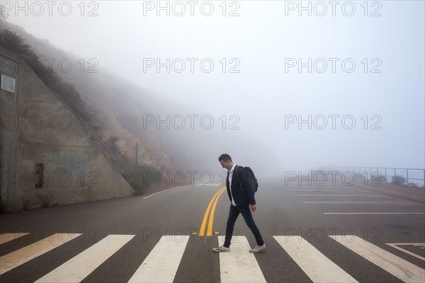 Caucasian man walking in crosswalk in fog