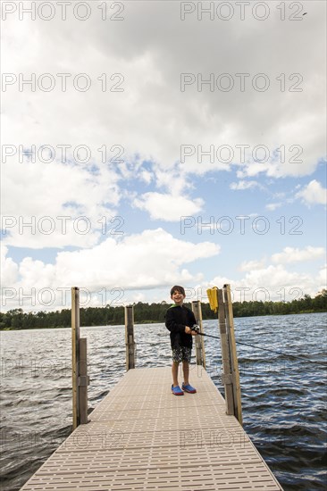 Mixed race boy fishing on dock