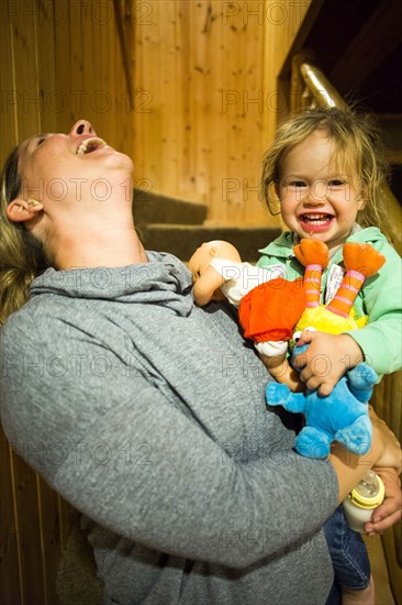 Laughing Caucasian mother holding daughter