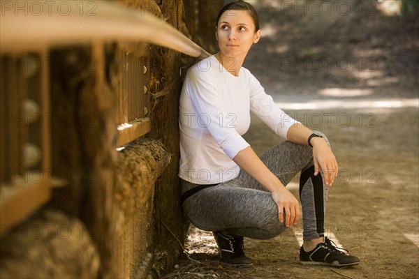 Curious woman crouching on forest path