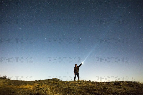 Caucasian man pointing flashlight at night sky