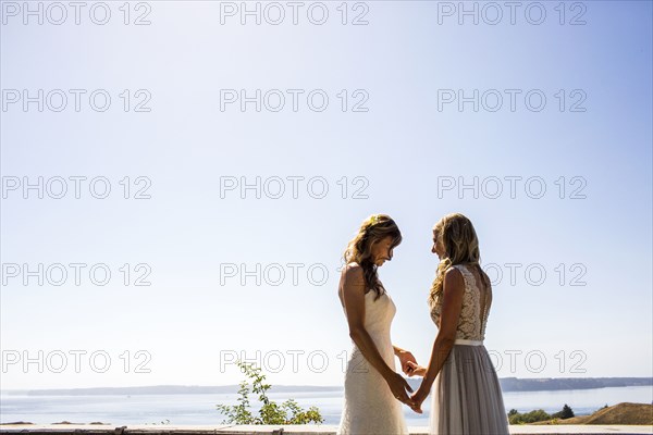 Caucasian brides holding hands at waterfront