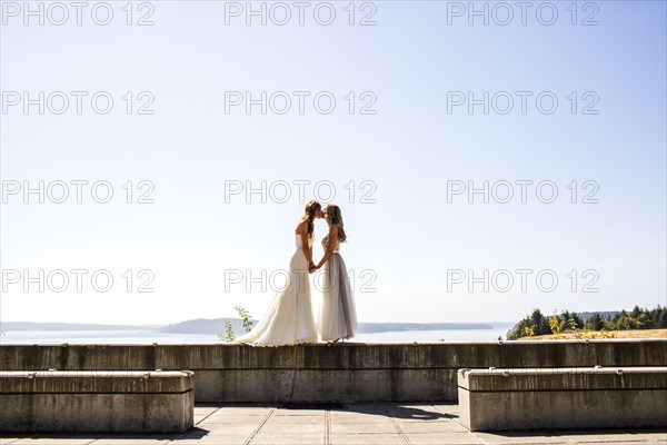 Caucasian brides kissing at waterfront