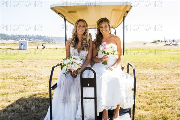 Caucasian brides sitting in golf cart
