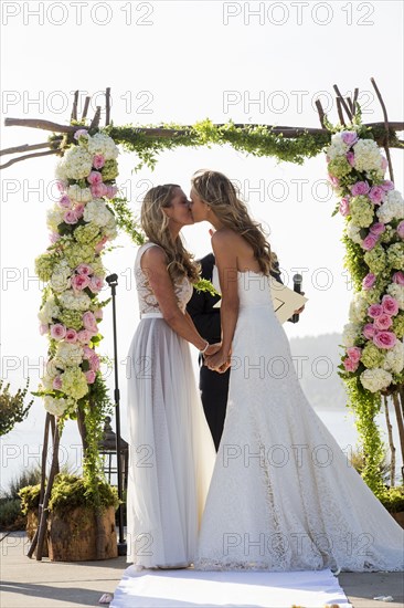 Caucasian brides kissing at wedding ceremony