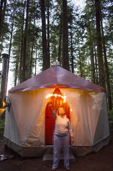 Caucasian woman waving sparkler outside yurt