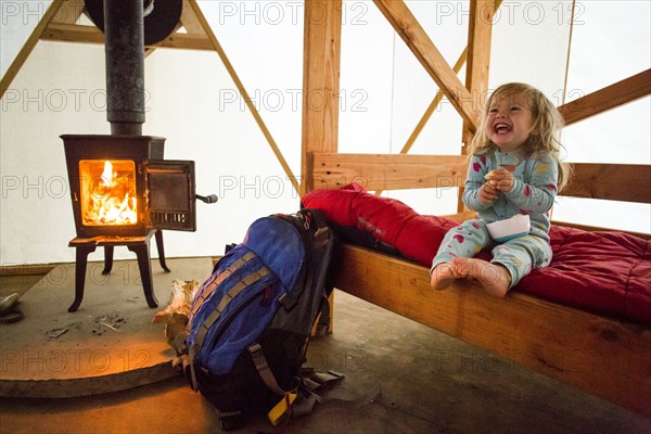 Caucasian girl laughing on bed in yurt