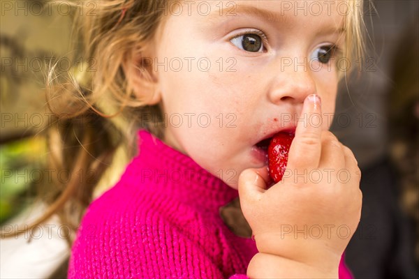 Caucasian girl eating strawberry