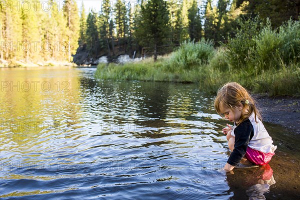 Caucasian girl crouching in river