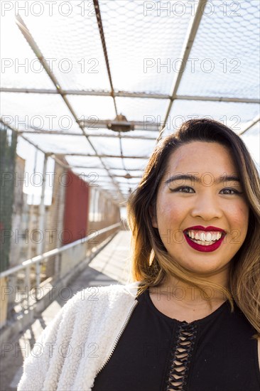 Asian woman smiling on footbridge