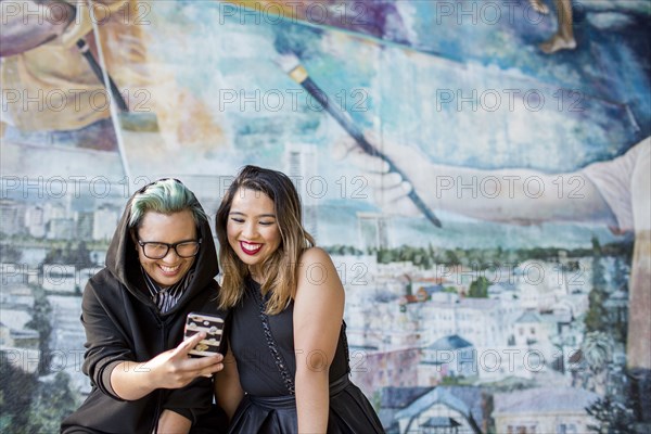 Smiling Asian women posing for cell phone selfie