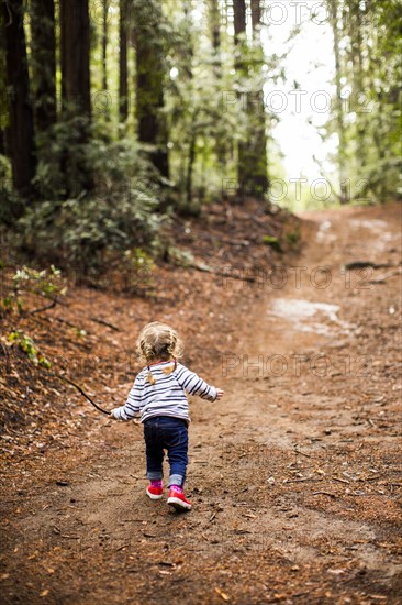 Caucasian girl walking on forest path