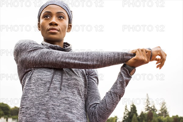 Serious Black athlete stretching arms