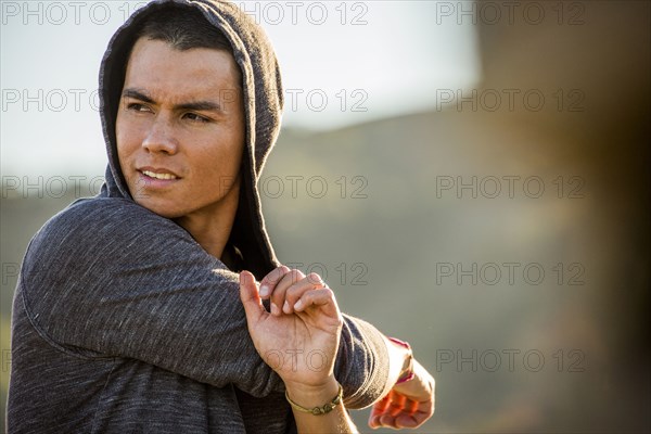 Serious Mixed Race man stretching arms