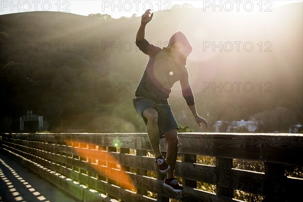 Mixed Race man jumping near railing on footbridge