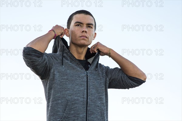 Serious Mixed Race man adjusting hoody