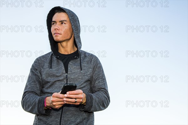 Mixed Race man wearing hoody texting on cell phone