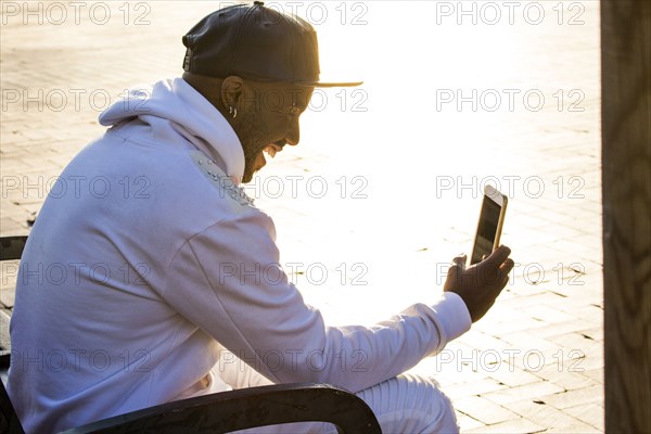 Laughing Black man texting on cell phone