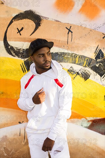 Serious Black man leaning on graffiti wall