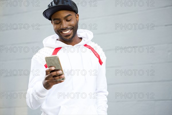 Smiling Black man texting on cell phone