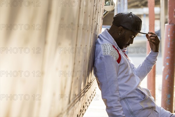 Serious Black man leaning on truck