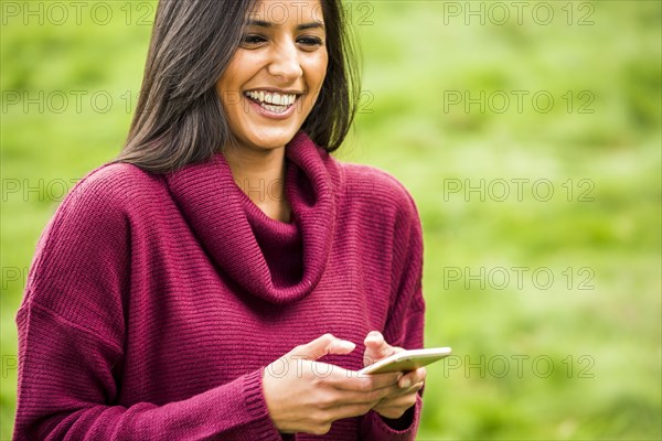 Laughing Indian woman texting on cell phone