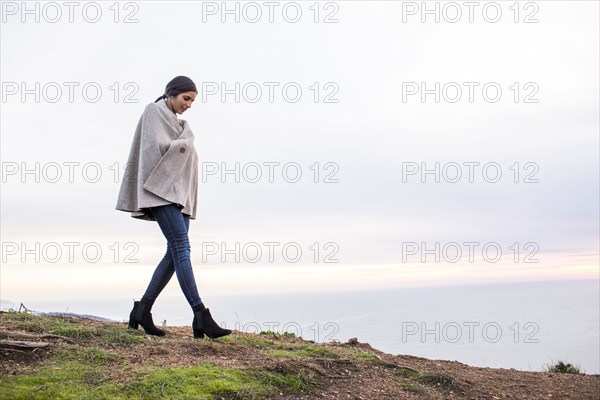 Indian woman wearing poncho walking on hill