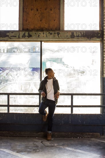 Smiling androgynous Mixed Race woman leaning on railing near window