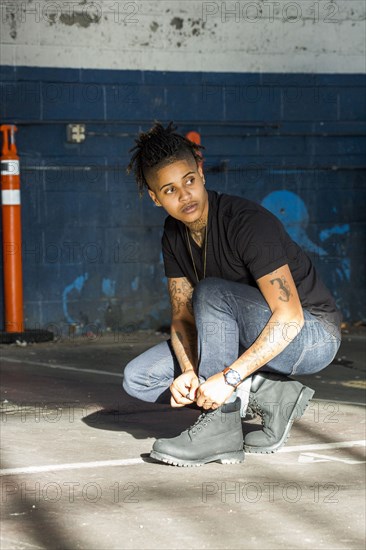 Androgynous Mixed Race woman tying shoelace