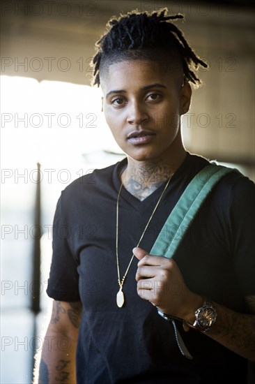 Portrait of androgynous Mixed Race woman carrying backpack