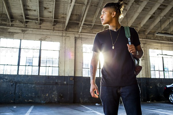 Serious androgynous Mixed Race woman carrying backpack