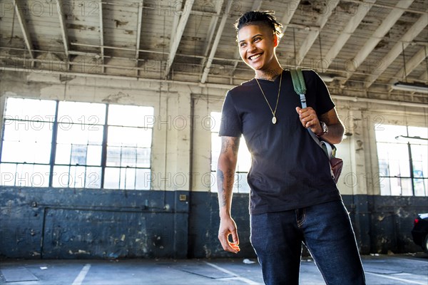 Smiling androgynous Mixed Race woman carrying backpack