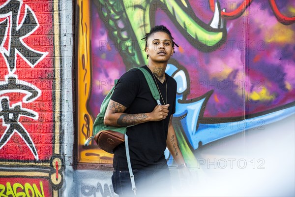 Portrait of androgynous Mixed Race woman near graffiti wall