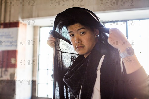 Androgynous Asian man holding scarf on head