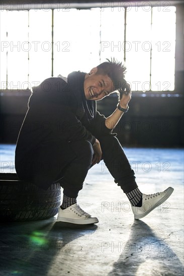 Laughing androgynous Asian man sitting on wheel