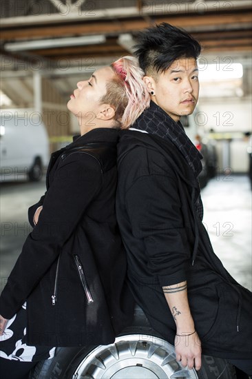 Androgynous Asian man and woman sitting on wheel