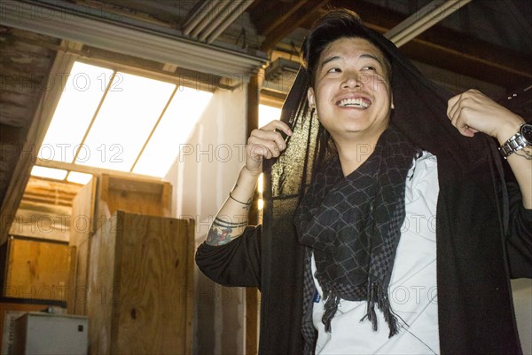 Androgynous Asian man holding scarf on head