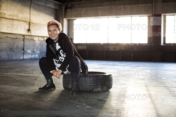 Portrait of smiling androgynous Asian woman sitting on wheel