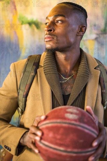 Black man wearing backpack holding basketball