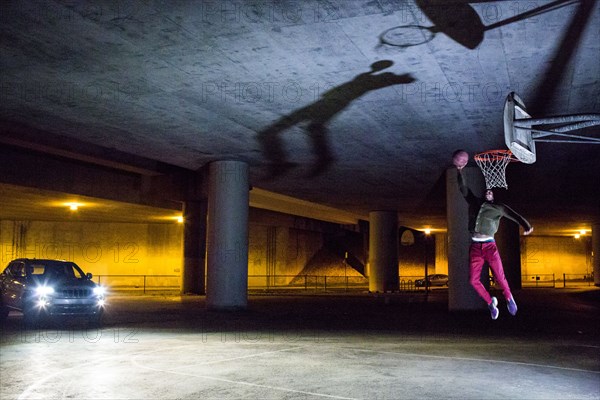 Headlights shining on Black man dunking basketball