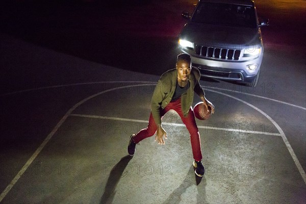 Headlights shining on Black man playing basketball