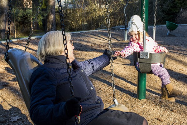 Caucasian grandmother and granddaughter on swings